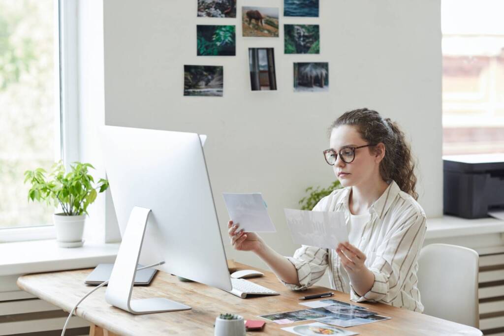 Female Photographer Holding Pictures at Desk
